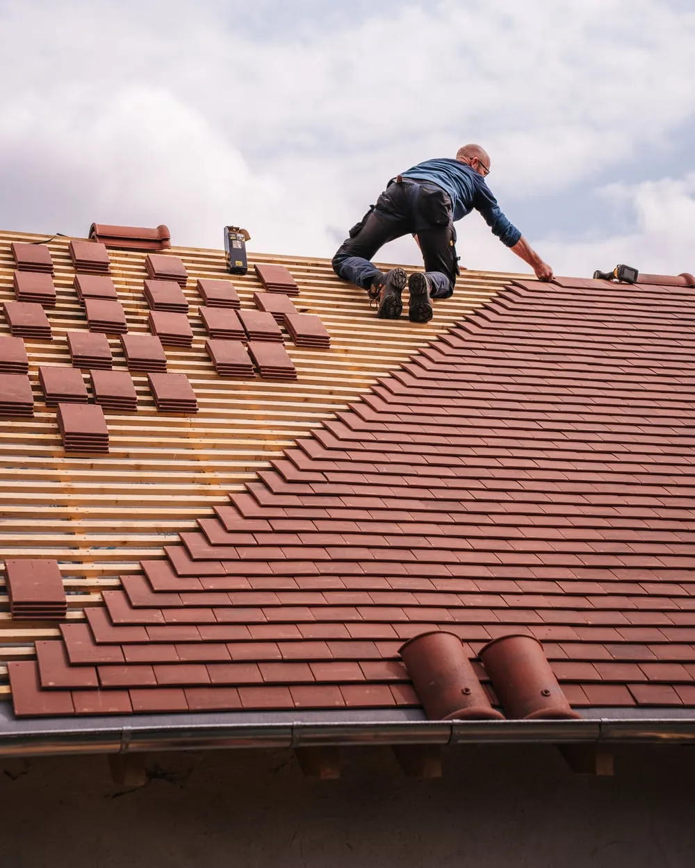 Dachdecker beim Verlegen von Dachziegeln auf einem Steildach