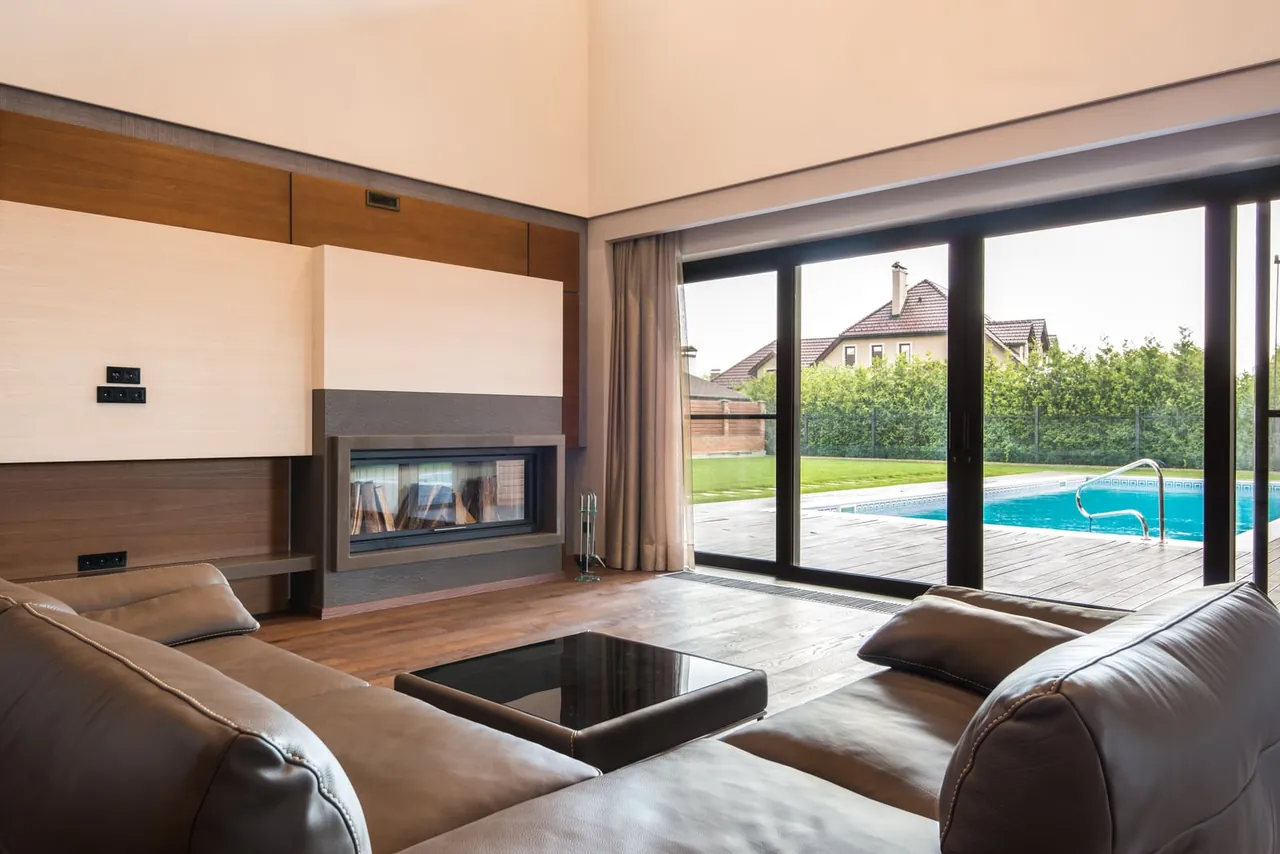 Wohnraum mit einer vom Fensterbauer eingebauten Glas-Schiebetür mit Blick auf Terrasse und Pool