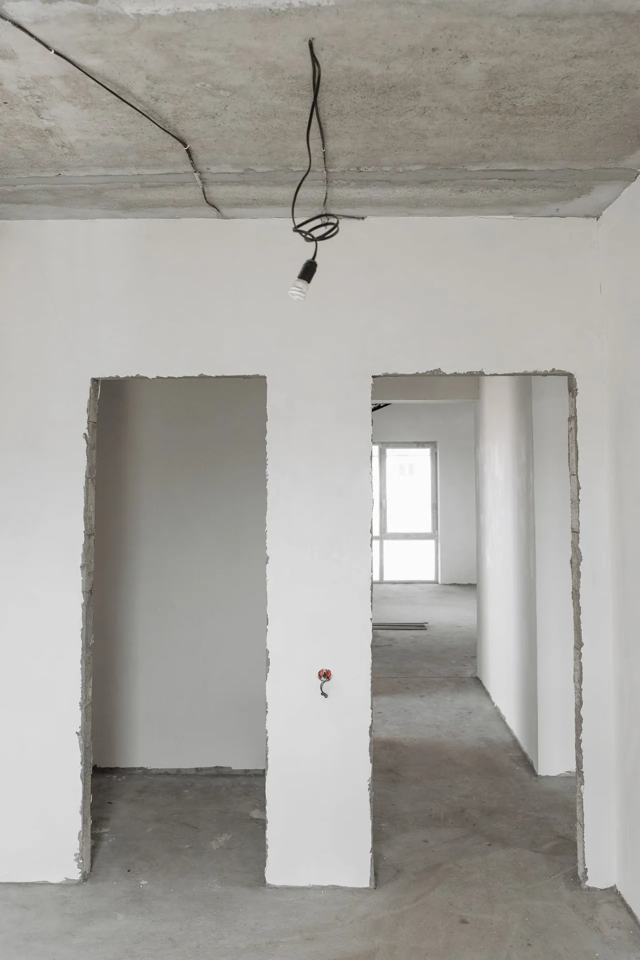 Vom Trockenbauer vorbereiteter Rohbau-Innenraum mit mehreren Türöffnungen und Betondecke